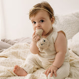 Baby in a cream outfit holding a plush toy on a braided Merino wool baby blanket.