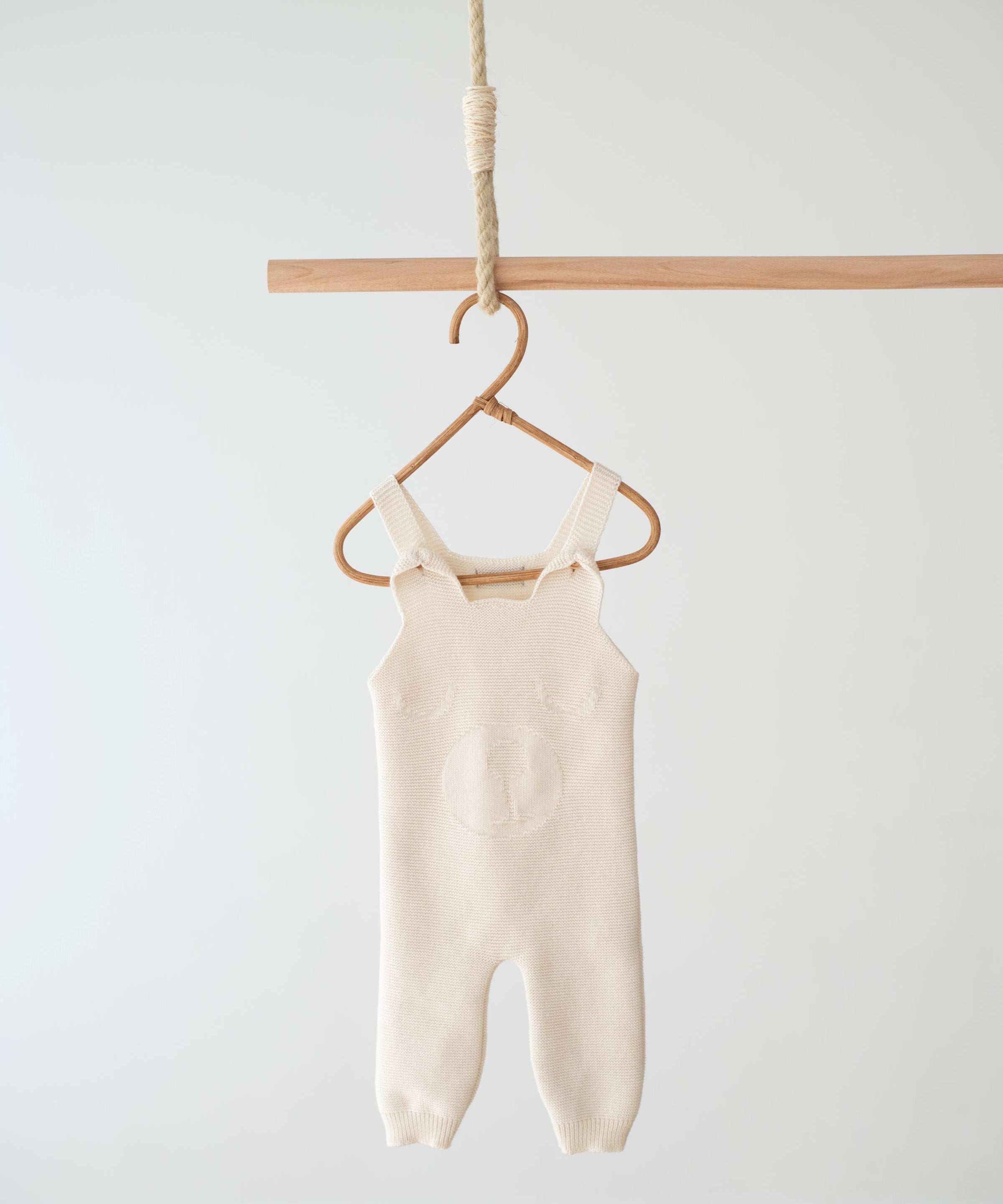 Full-length Jakopina Teddy Bear Romper Long in cream organic cotton knit with wooden buttons.